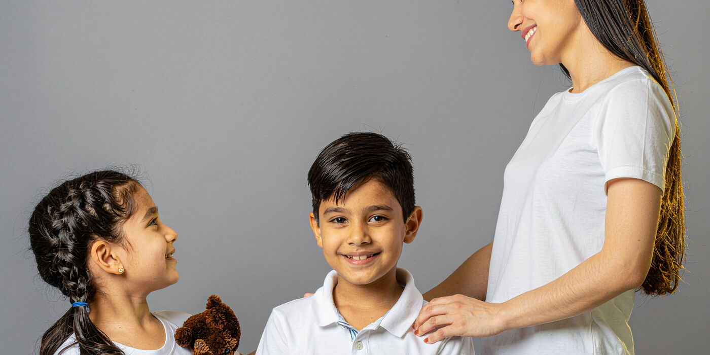 Zwei Kinder und eine Frau lächeln. Hilfe & Begleitung.